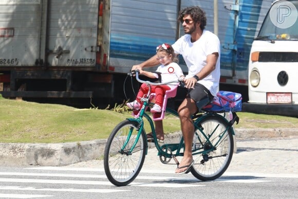 Filha de Deborah Secco e Hugo Moura, Maria Flor sentou na cadeirinha da frente da bicicleta do pai