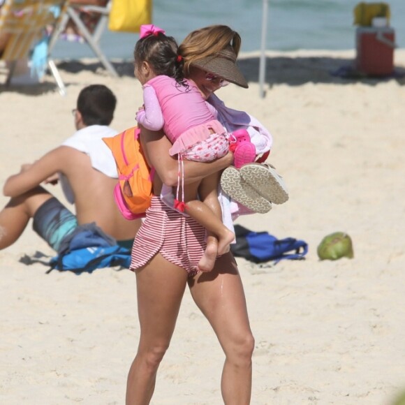 Deborah Secco deixa a praia com a filha, Maria Flor, nos braços