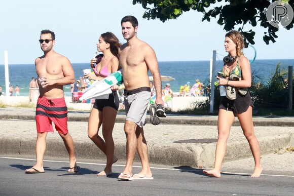 Namorada de Cauã Reymond, Mariana Goldfarb caminha com amigos na praia da Barra da Tijuca