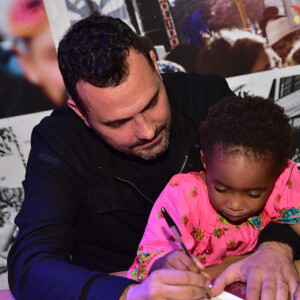 Filha de Ale Youssef e Leandra Leal, Julia segura a caneta com o pai enquanto ele autografa livro