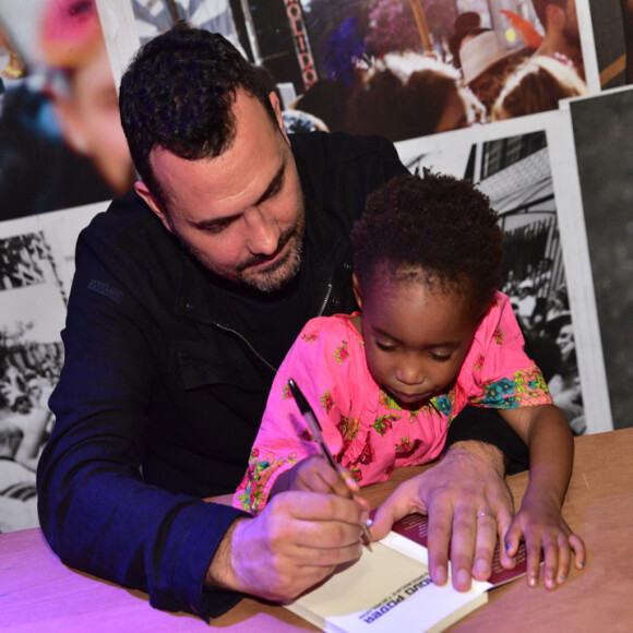 Filha de Ale Youssef e Leandra Leal, Julia segura a caneta com o pai enquanto ele autografa livro