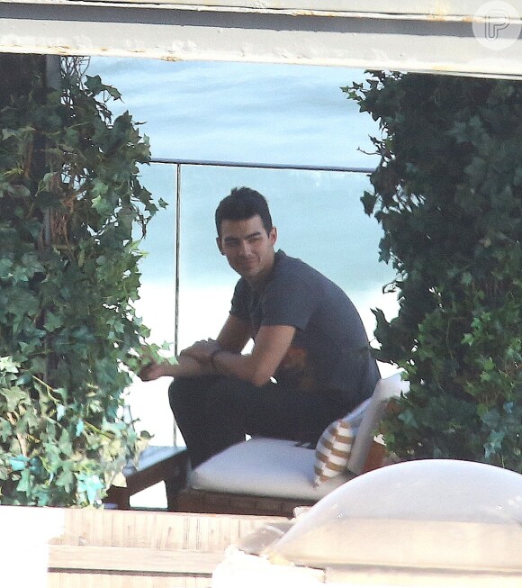 Joe Jonas chegou tímido ao terraço do hotel, vestindo calça comprida e camisa