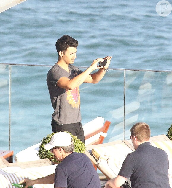 De calça e blusa escuras, Joe Jonas apreciou a vista da praia de Ipanema, na Zona Sul da cidade e fez questão de tirar uma foto da paisagem