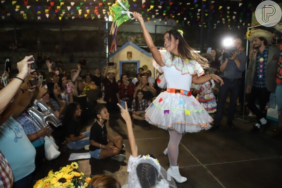 Carol Peixinho joga seu buquê de noiva de brincadeira em festa junina