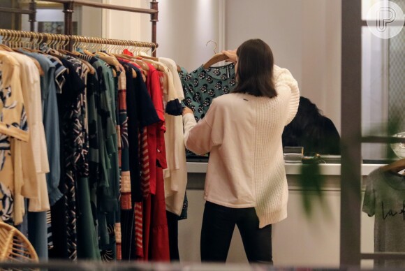 Camila Queiroz analisa peças de roupas de loja na arara