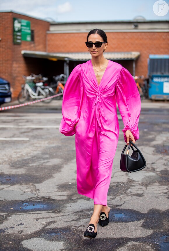 Vestido com mangas amplas em rosa neon e bolsa de mão em um look ultrafeminino para o verão 2020