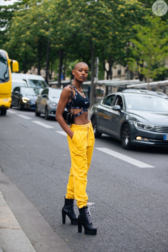 Moda streetwear 2020: calça jogger amarela faz dupla com top esportivo em look fashionista. Para arrematar, bota de salto com cadarço é uma opção