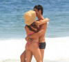 Isis Valverde troca carinho com o marido na praia da Barra da Tijuca