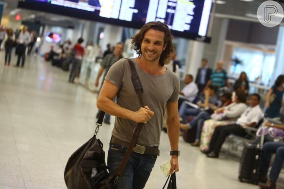 Igor Rickli caminha sorridente no aeroporto