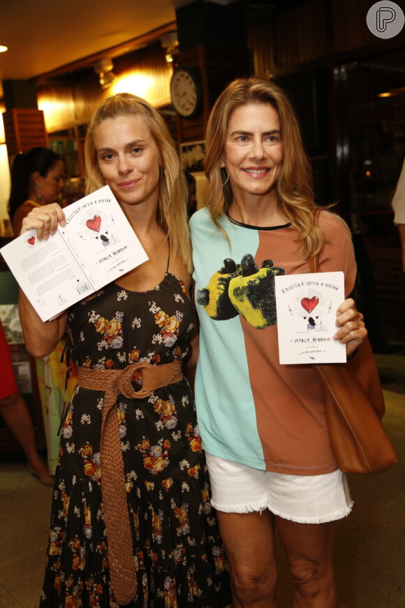 Carolina Dieckmann posou exibindo o livro da amiga Maria Ribeiro ao lado de Maitê Proença, que prestigiou a noite com um shortinho e as pernas de fora