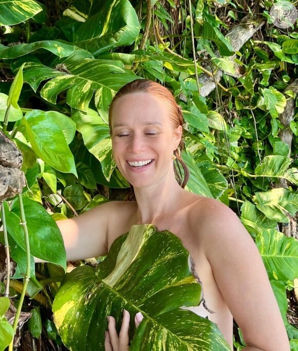 Mariana Ximenes apareceu com um sorriso radiante sendo coberta apenas por uma folha