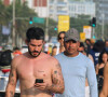 Ao caminhar com Sophie Charlotte na orla do Rio, Pedro Neschling não desgrudou de seu celular antes de gravar cena da novela 'Renascer'