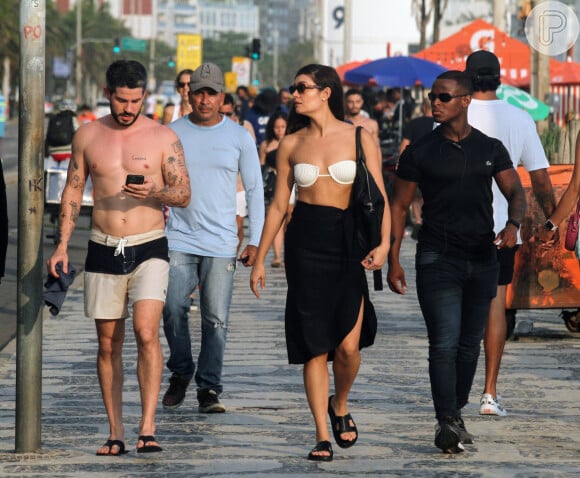 Ao caminhar com Sophie Charlotte na orla do Rio, Pedro Neschling não desgrudou de seu celular antes de gravar cena da novela 'Renascer'