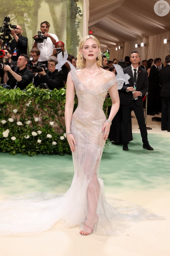 Um dos mais elogiados looks do MET Gala 2024 foi o da atriz Elle Fanning. Ela escolheu um vestido transparente com flores esculpiads em gelo naos ombros 