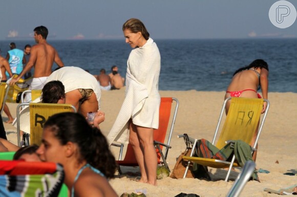 Maitê Proença se enroça em uma toalha ao sair do mar