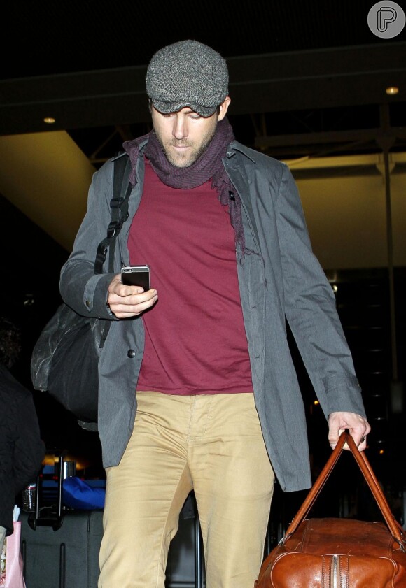Ryan Reynolds checa o celular em aeroporto
