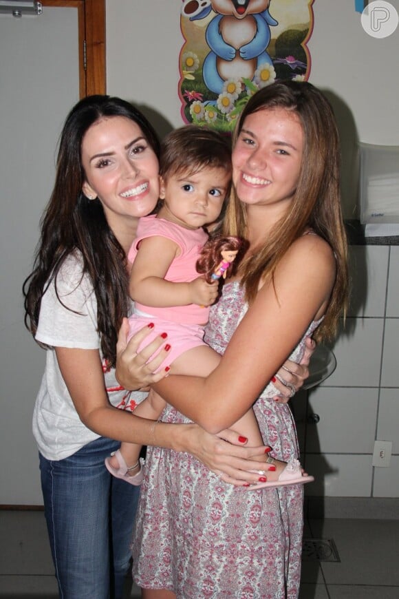 Lisandra Souto e a filha mais velha, Yasmin, posam com criança atendida pela instituição