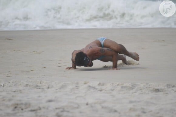 Juliano Cazarré faz posição de ioga na praia