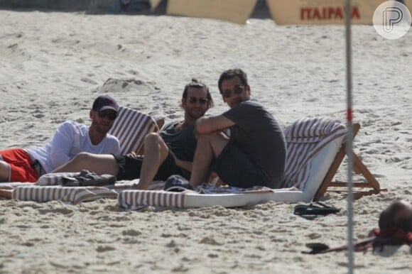 Bradley Cooper relaxa em espreguiçadeira na praia de Ipanema