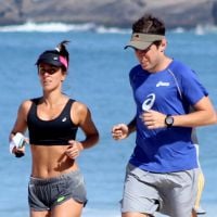 Carol Barcellos mostra barriga sequinha durante corrida na praia com o marido