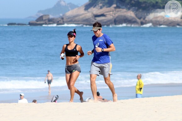 Carol Barcellos mostra barriga sequinha durante corrida na praia com o marido, nesta quarta-feira, 20 de maio de 2015a