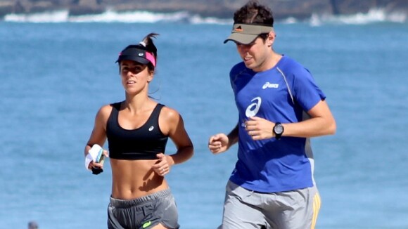 Carol Barcellos mostra barriga sequinha durante corrida na praia com o marido