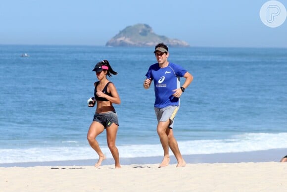 Carol Barcellos mostra barriga sequinha durante corrida na praia com o marido, nesta quarta-feira, 20 de maio de 2015a