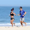 Carol Barcellos mostra barriga sequinha durante corrida na praia com o marido, nesta quarta-feira, 20 de maio de 2015a