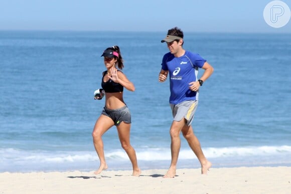 Carol Barcellos mostra barriga sequinha durante corrida na praia com o marido, nesta quarta-feira, 20 de maio de 2015a