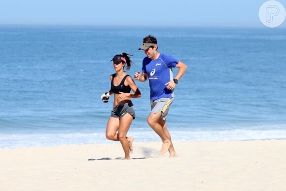 Carol Barcellos mostra barriga sequinha durante corrida na praia com o marido, nesta quarta-feira, 20 de maio de 2015a