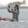 Marina Ruy Barbosa tira fotos com o celular em uma praia do Rio de Janeiro