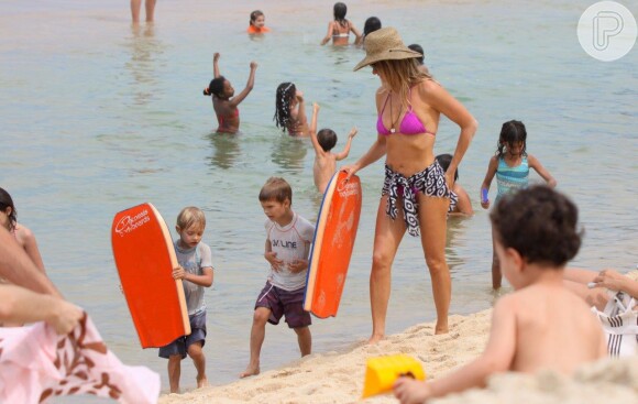 Fernanda Lima ajuda os filhos, João e Francisco, a carregarem as suas pranchas