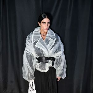 Thai de Melo Bufrem apostou em um look marcado por transparência, volume e contraste de texturas para o evento fashion. A empresária usou um casaco de tule branco transparente e volumoso, com lapelas largas e mangas bufantes, sobre blusa preta e saia longa plissada
