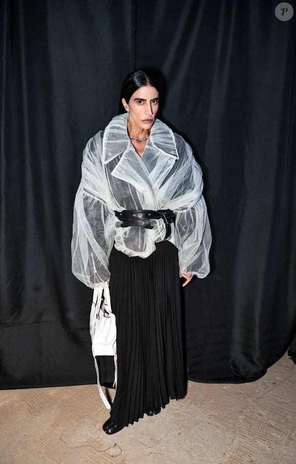 Thai de Melo Bufrem apostou em um look marcado por transparência, volume e contraste de texturas para o evento fashion. A empresária usou um casaco de tule branco transparente e volumoso, com lapelas largas e mangas bufantes, sobre blusa preta e saia longa plissada