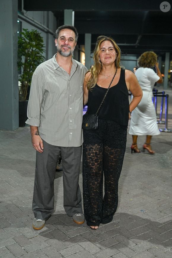 Carol Sampaio apostou no charme e transparência com uma regata preta básica combinada com uma calça pantalona de renda preta trabalhada. Ela complementou o visual com uma bolsa tiracolo de matelassê preta da Chanel. Ao seu lado, seu marido vestia uma camisa de listras finas com mangas dobradas, calça cinza de alfaiataria e tênis casuais em tons neutros
