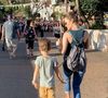 Sandy e Theo caminham no que parece ser o parque da Disney. Mãe e filho fazem uma coreografia sincronizada enquanto andam