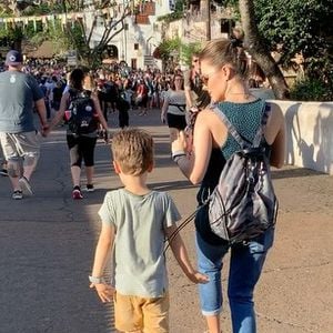 Sandy e Theo caminham no que parece ser o parque da Disney. Mãe e filho fazem uma coreografia sincronizada enquanto andam