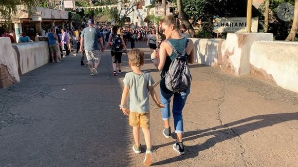 Sandy e Theo caminham no que parece ser o parque da Disney. Mãe e filho fazem uma coreografia sincronizada enquanto andam