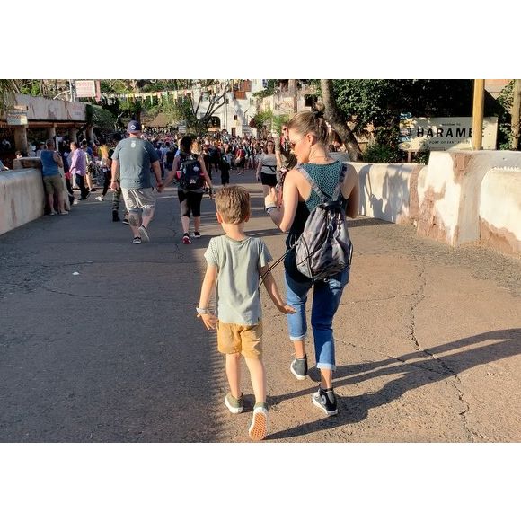 Sandy e Theo caminham no que parece ser o parque da Disney. Mãe e filho fazem uma coreografia sincronizada enquanto andam