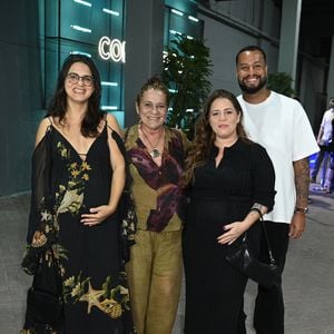 Grávida, Tati Machado surgiu elegante em um vestido midi preto canelado de mangas compridas e gola polo, combinado com mocassins pretos e bolsa de ombro. Ao seu lado, a acompanhante à esquerda usou um vestido longo preto fluído com estampa marinha e mangas caídas, enquanto a acompanhante ao centro vestia um conjunto verde-oliva com camisa estampada. O companheiro à direita completou o grupo com uma camiseta branca oversize, calça preta e sapatos casuais