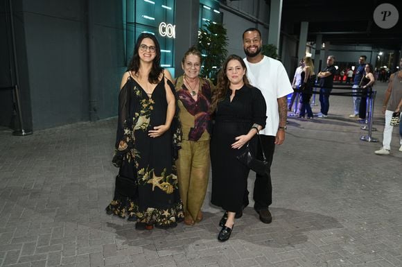 Grávida, Tati Machado surgiu elegante em um vestido midi preto canelado de mangas compridas e gola polo, combinado com mocassins pretos e bolsa de ombro. Ao seu lado, a acompanhante à esquerda usou um vestido longo preto fluído com estampa marinha e mangas caídas, enquanto a acompanhante ao centro vestia um conjunto verde-oliva com camisa estampada. O companheiro à direita completou o grupo com uma camiseta branca oversize, calça preta e sapatos casuais