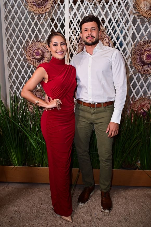 Thaynara OG e André Ferraz: a anfitriã surgiu deslumbrante em um vestido longo drapeado vermelho de gola alta e silhueta ajustada, combinado com sapatos nude. Ao seu lado, o acompanhante escolheu a sobriedade com camisa social branca de punhos estruturados, calça de sarja verde-oliva, cinto e sapatos marrons