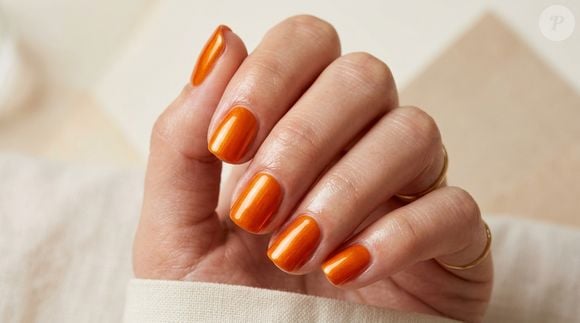 Para quem quer fugir dos tons discretos, o laranja dopamina é uma aposta certeira para a primavera. A versão brilhante e metalizada transforma as unhas curtas em protagonistas do look