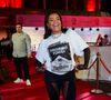Tati Quebra Barraco trouxe a irreverência do Rio para o tapete. A funkeira ousou e utilizou uma camiseta oversized branca com uma estampa frontal provocativa que simula um maço de cigarros com o aviso 'Proibido Fumar'. Para elevar o visual ao contexto de gala, ela combinou a peça com luvas de tule pretas que se estendem até os ombros e uma calça legging com recortes em transparência, finalizando com botas de salto tratorado e colares de corrente prateada.