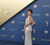 Zendaya ostenta um vestido coluna translúcido de tom prateado, inteiramente bordado com cristais e aplicações reluzentes que criam um efeito efervescente de brilho por toda a silhueta