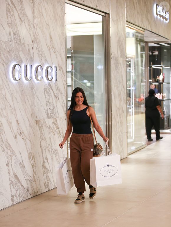 Duda Guerra sorrindo com bolsas de luxo