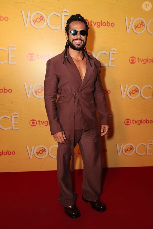 Amaury Lorenzo investe na elegância contemporânea com terno monocromático em tom marrom-feijão, composto por paletó envelope com amarração lateral em faixa e calça reta de caimento fluido. Nos acessórios, destaca-se o uso de óculos escuros e sapatos sociais escuros