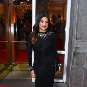 Dira Paes escolheu um vestido preto de mangas longas e gola alta, cuja sobriedade é quebrada por um trabalho primoroso de pedrarias no decote e nos punhos. Os cristais prateados e fumê formam uma espécie de colar integrado à peça, trazendo luz direta para o rosto. O corte reto do vestido garante uma silhueta alongada e atemporal