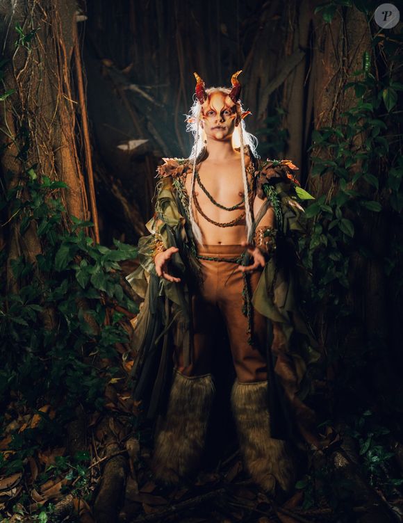 João Victor Gonçalves, o Mau Mau de 'Quem Ama Cuida' apostou em um look todo inspirado no deus Pã: o look é composto por uma capa em camadas de tecidos fluídos e esfarrapados em tons de verde-oliva e marrom, decorada com folhagens nos ombros. O peitoral fica à mostra, adornado por cordões trançados em tom terroso, acompanhado por calça justa marrom com cinto trançado e polainas felpudas de pele sintética nos pés. Nos braços, ostenta braçadeiras estruturadas com detalhes folhosos. O destaque fica para a caracterização facial, que inclui próteses de chifres avermelhados, orelhas pontudas, maquiagem artística facial e longas mechas brancas