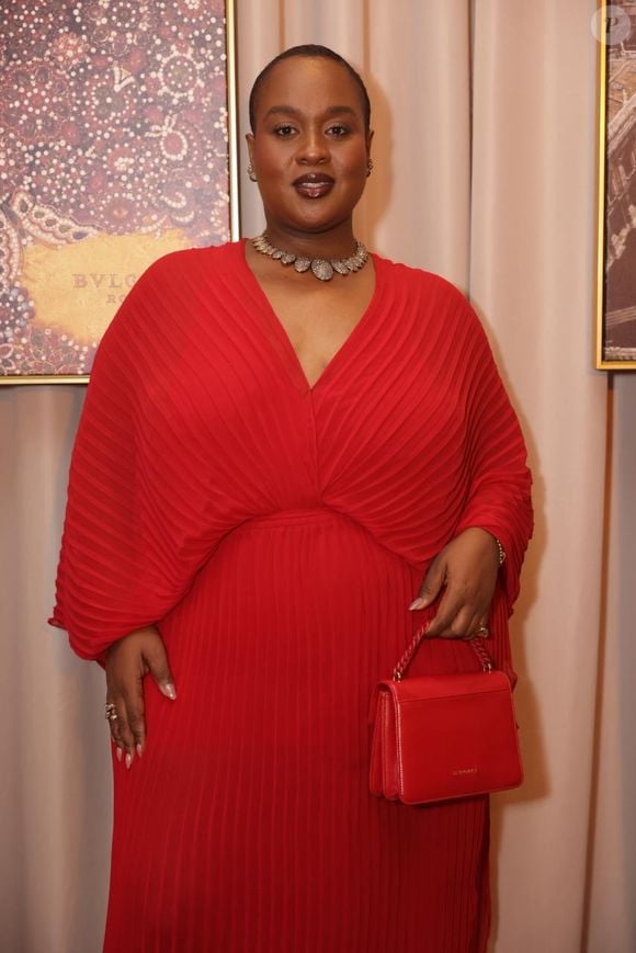 Evidenciando uma curadoria minuciosa para a noite da Bulgari, o visual é coordenado com uma bolsa de mão estruturada em couro também vermelho com alça de corrente dourada, escarpins com estampa xadrez que quebram sutilmente a unidade cromática nos pés e uma imponente gargantilha cravejada de pedrarias rente ao pescoço, unindo audácia e sofisticação maximalista